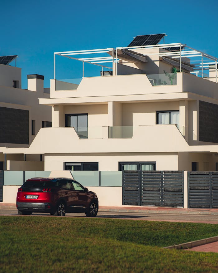 Elegant modern townhouse featuring solar panels with a car parked nearby, bathed in daylight.